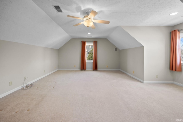 additional living space with visible vents, baseboards, a textured ceiling, and lofted ceiling