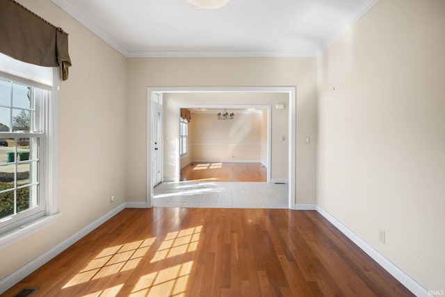 corridor featuring an inviting chandelier, wood finished floors, baseboards, and ornamental molding