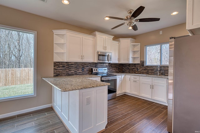 kitchen featuring open shelves, white cabinets, a peninsula, and stainless steel appliances