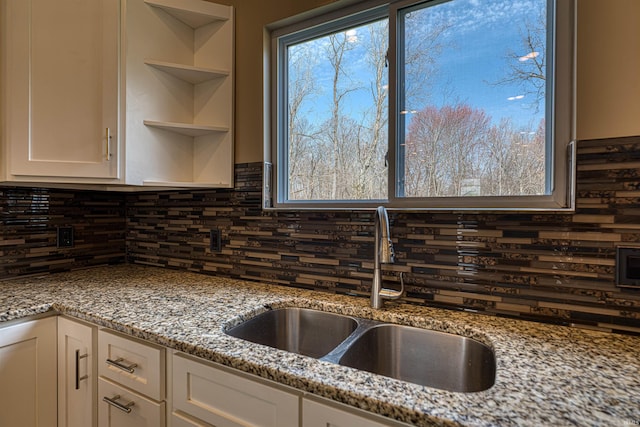 kitchen with tasteful backsplash, white cabinetry, and a sink