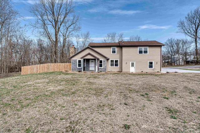 back of property featuring a yard, a chimney, and fence