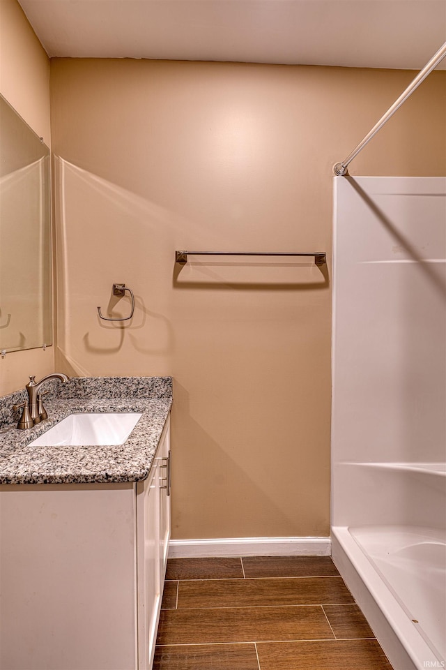 full bathroom with walk in shower, vanity, baseboards, and wood tiled floor