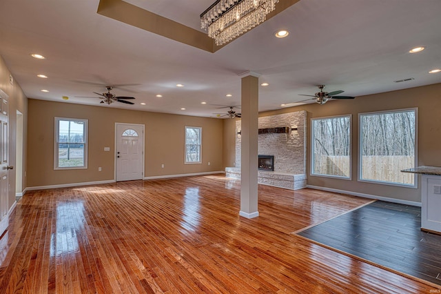 unfurnished living room with visible vents, a fireplace, ceiling fan, light wood-type flooring, and a wealth of natural light