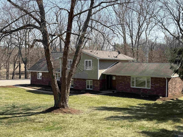 split level home featuring a front lawn and brick siding