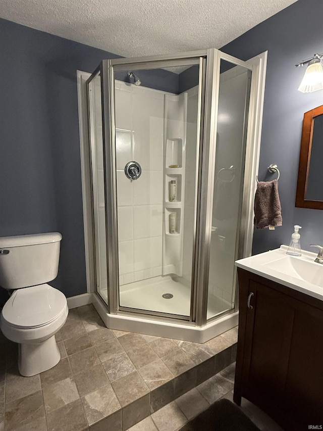 bathroom with baseboards, toilet, a stall shower, a textured ceiling, and vanity