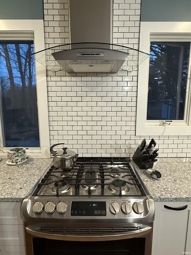 kitchen with white cabinetry, gas range, backsplash, and extractor fan