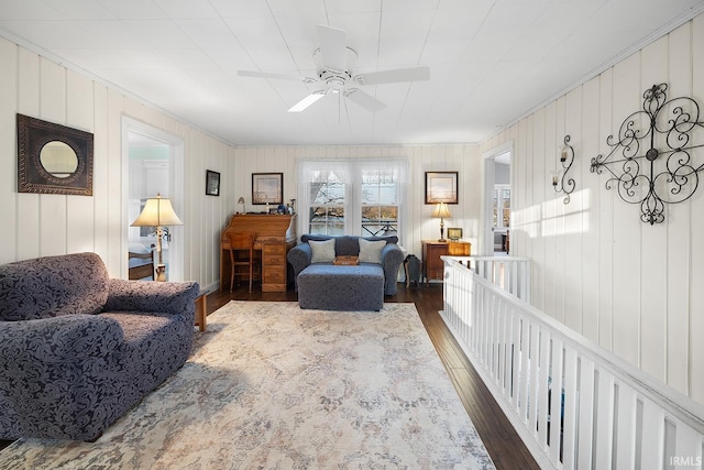 living area featuring wood finished floors, ceiling fan, and crown molding