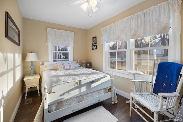 bedroom featuring multiple windows, a ceiling fan, baseboards, and wood finished floors