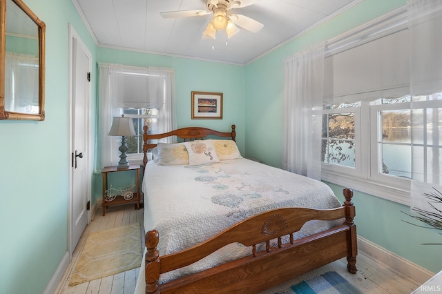 bedroom with wood finished floors, baseboards, and ornamental molding