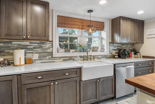 kitchen with light wood-style flooring, a sink, backsplash, dishwasher, and hanging light fixtures