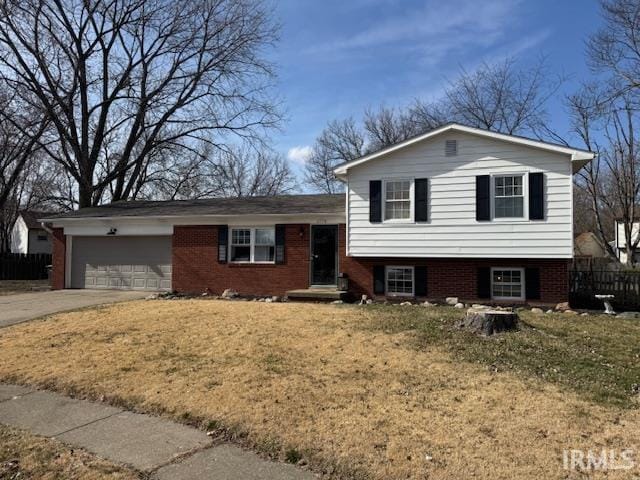 tri-level home with driveway, fence, a front yard, an attached garage, and brick siding