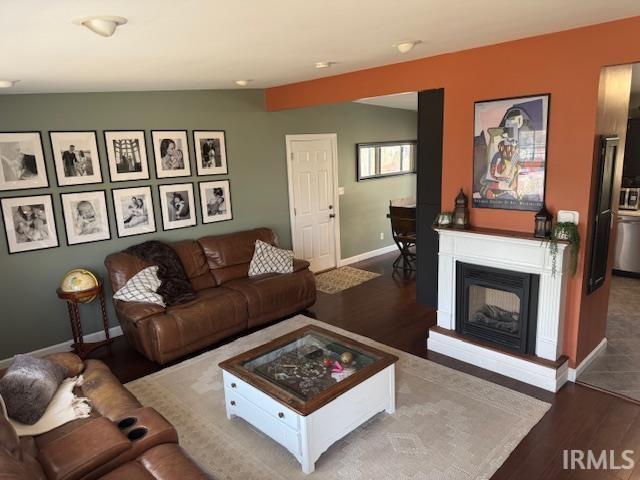 living room with a glass covered fireplace, baseboards, and wood finished floors