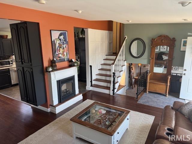 living room with stairway, dark wood-style floors, and a fireplace with raised hearth