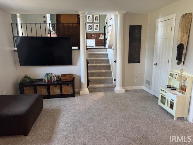 living area with visible vents, baseboards, stairs, carpet flooring, and ornate columns