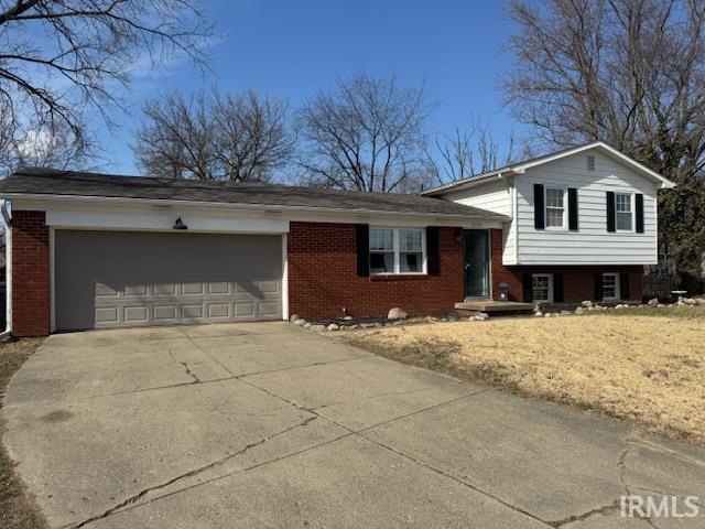 tri-level home featuring brick siding, a garage, and driveway