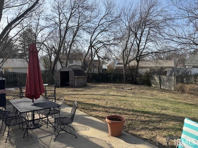 view of yard with outdoor dining space, a patio, a fenced backyard, a storage shed, and an outdoor structure