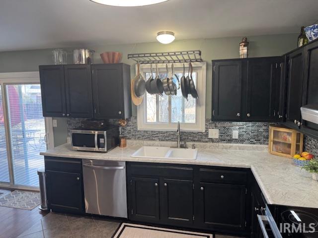 kitchen with a sink, decorative backsplash, appliances with stainless steel finishes, and light countertops