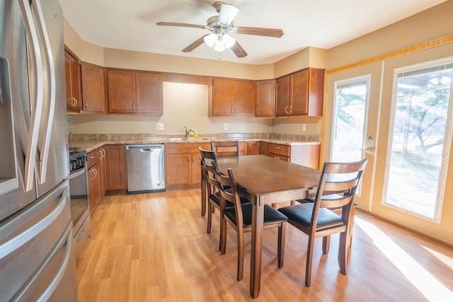 kitchen featuring brown cabinets, stainless steel appliances, light wood-style floors, and a sink