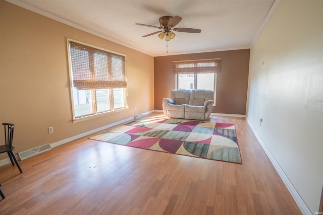 living room with crown molding, wood finished floors, visible vents, and ceiling fan