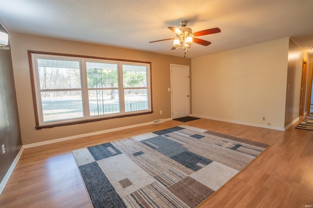 entryway with visible vents, a textured ceiling, light wood-style floors, baseboards, and ceiling fan