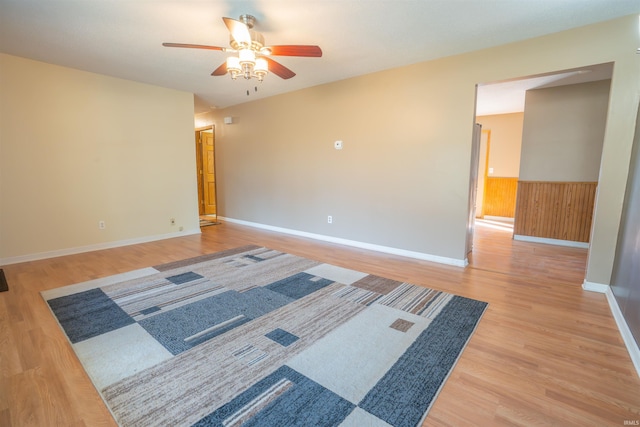 spare room featuring a ceiling fan, light wood-style floors, and wainscoting