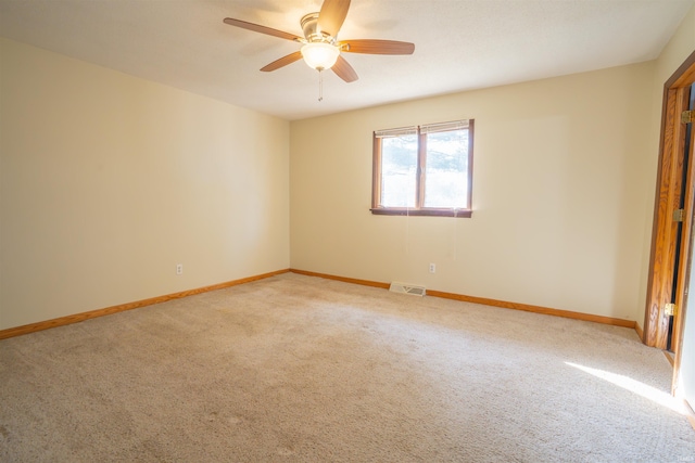 carpeted empty room with a ceiling fan, visible vents, and baseboards