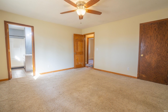 unfurnished bedroom with light colored carpet, a ceiling fan, ensuite bathroom, and baseboards