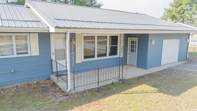 view of front of house with a front lawn, a garage, driveway, and metal roof