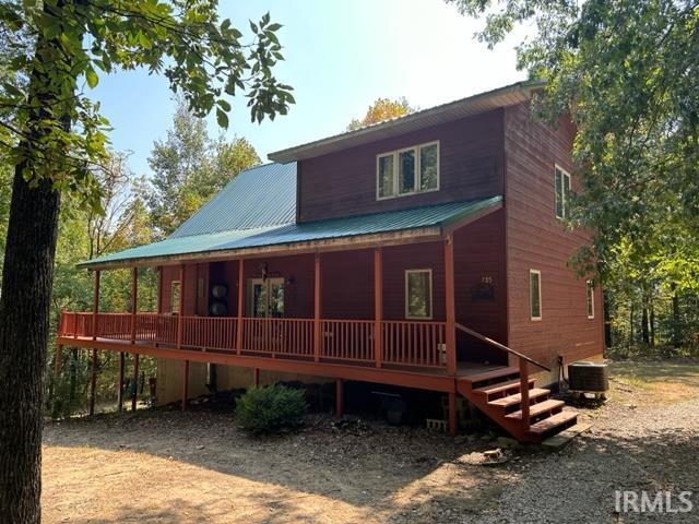 rear view of property featuring cooling unit, a porch, and metal roof