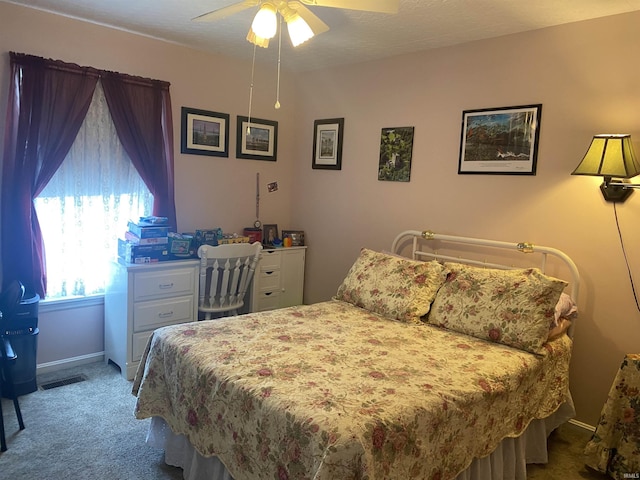 carpeted bedroom with visible vents, baseboards, and a ceiling fan