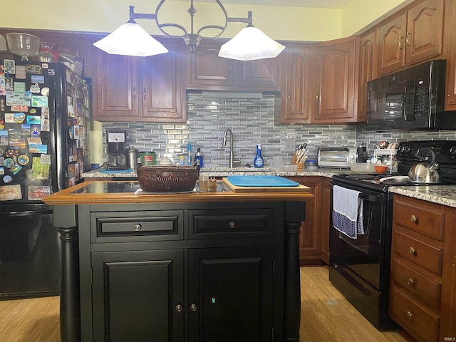 kitchen with decorative backsplash, light wood-style flooring, black appliances, and light stone countertops