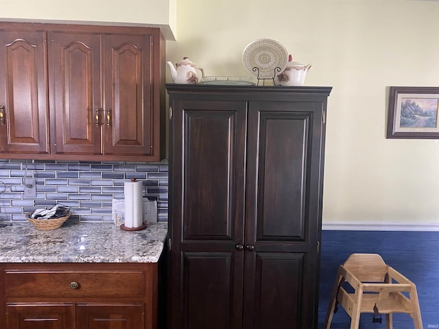 kitchen with dark brown cabinets, light stone countertops, and tasteful backsplash