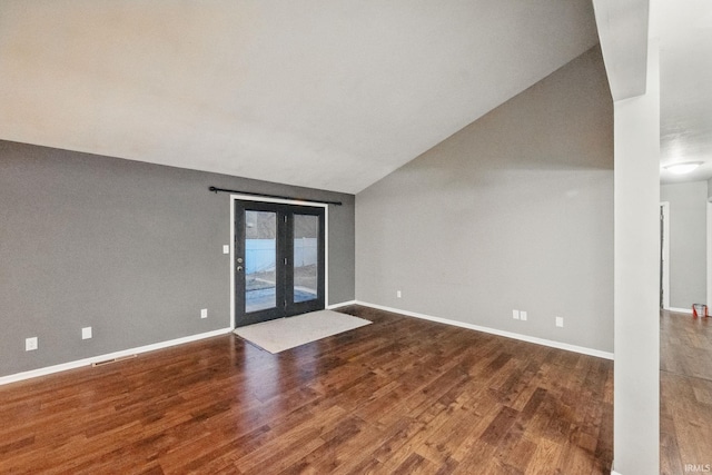 empty room featuring visible vents, lofted ceiling, baseboards, and wood finished floors