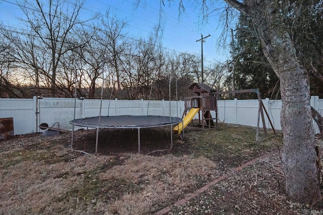 view of yard with a trampoline, a fenced backyard, and a playground