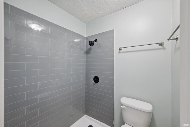 full bath with toilet, a textured ceiling, and tiled shower