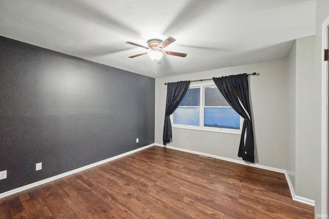 spare room with visible vents, wood finished floors, baseboards, and ceiling fan