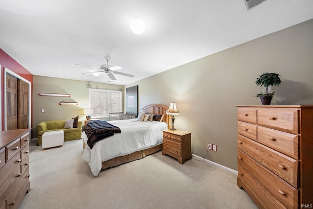 bedroom featuring visible vents, light colored carpet, baseboards, and ceiling fan