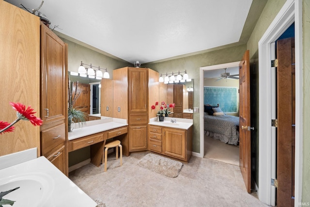 bathroom with a sink, ensuite bath, a ceiling fan, and two vanities