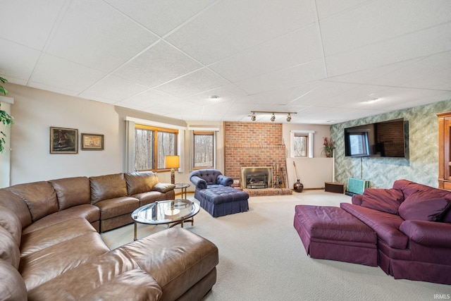 living area featuring track lighting, a brick fireplace, carpet, and a drop ceiling