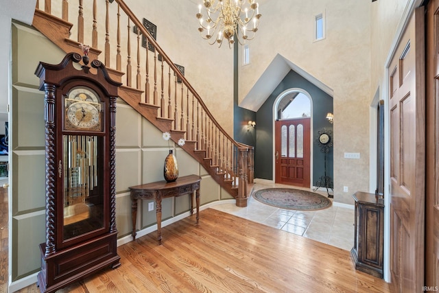 entryway with a notable chandelier, a high ceiling, wood finished floors, and stairs