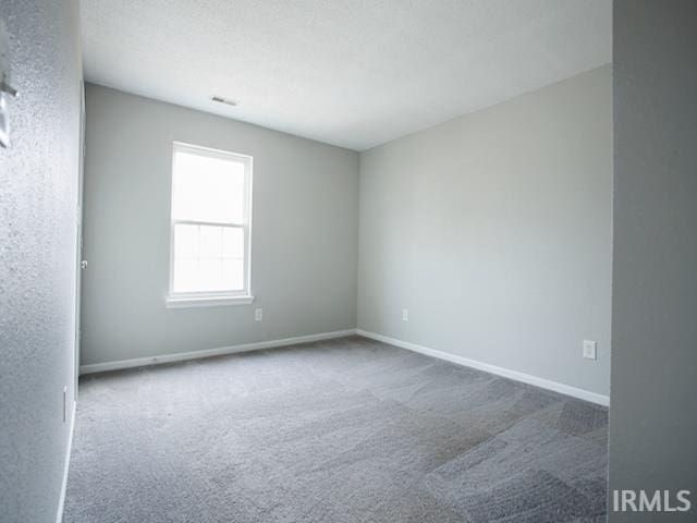 unfurnished room featuring carpet flooring, visible vents, and baseboards