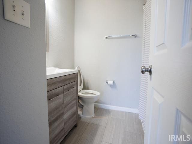 bathroom with vanity, toilet, and baseboards