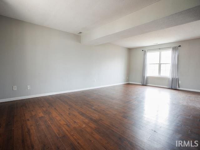 spare room featuring dark wood-style floors and baseboards