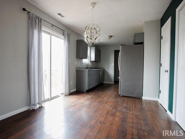 kitchen with visible vents, freestanding refrigerator, gray cabinetry, dark wood-type flooring, and a notable chandelier