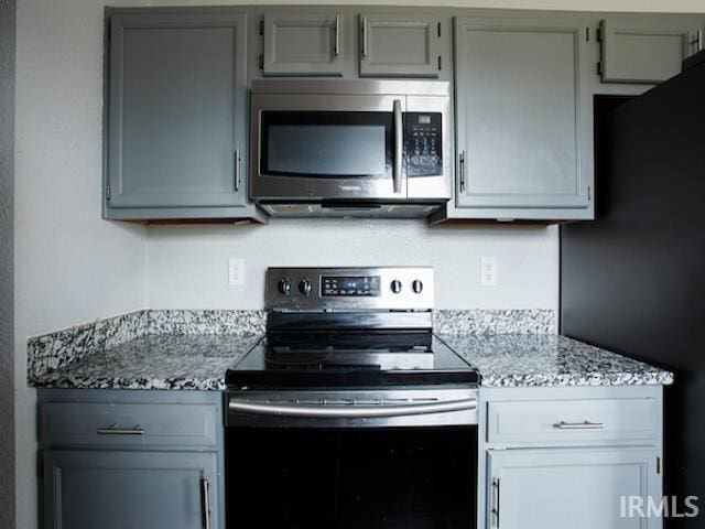 kitchen featuring light stone countertops, gray cabinets, and stainless steel appliances