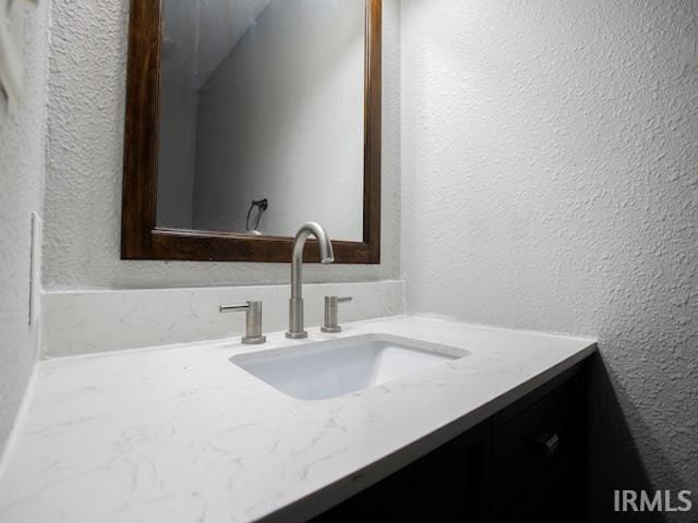 bathroom featuring vanity and a textured wall