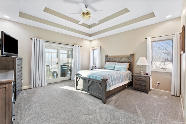 bedroom featuring access to exterior, multiple windows, and a tray ceiling