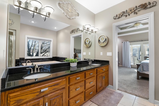 bathroom featuring tile patterned floors, double vanity, ensuite bathroom, and a sink