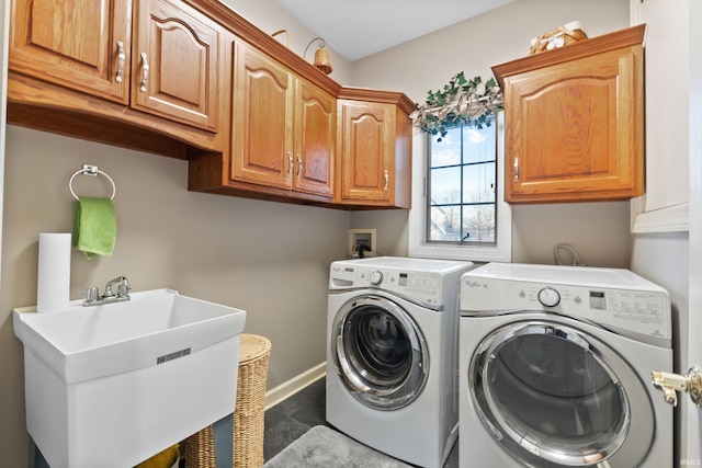 clothes washing area with baseboards, cabinet space, independent washer and dryer, and a sink