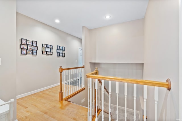 hallway featuring wood finished floors, recessed lighting, an upstairs landing, and baseboards